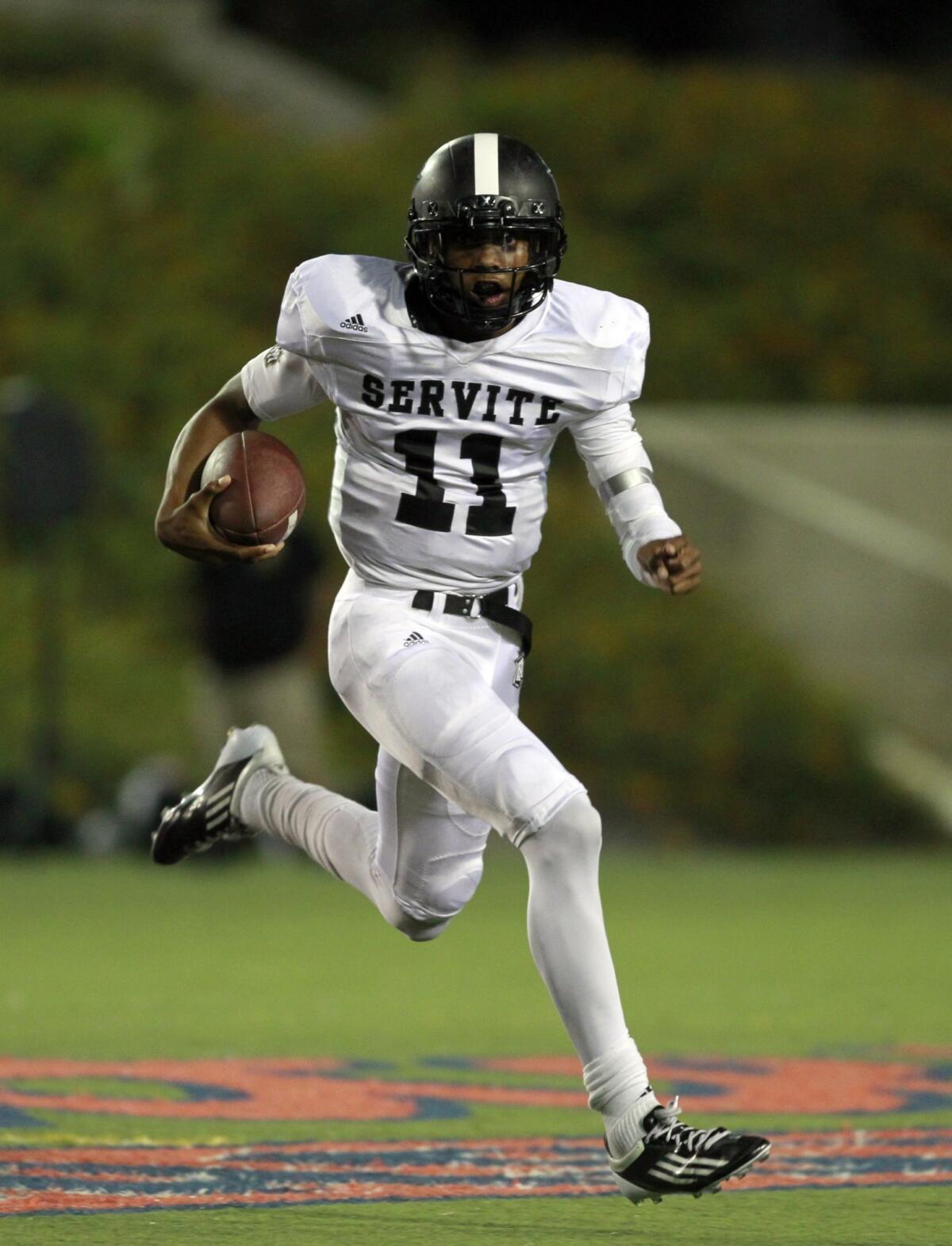 Servite quarterback Travis Waller runs the ball during a game against Edison last month. Servite moves up one spot in this week's rankings following its win Friday over Santa Margarita.