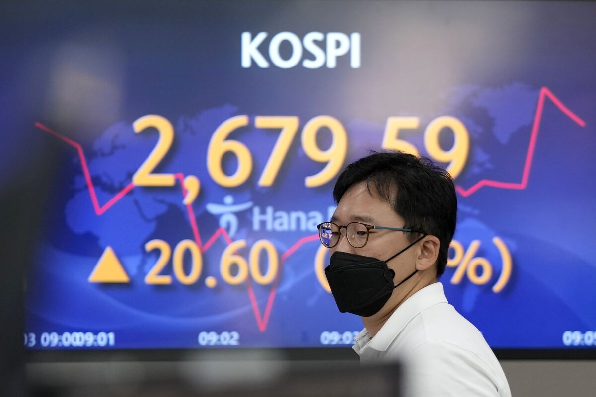 A currency trader walks by the screens showing the Korea Composite Stock Price Index (KOSPI) at a foreign exchange dealing room in Seoul, South Korea, Friday, June 3, 2022. Asian shares rose Friday amid mixed signs for investors such as rising energy prices and COVID-19 restrictions easing in China. (AP Photo/Lee Jin-man)