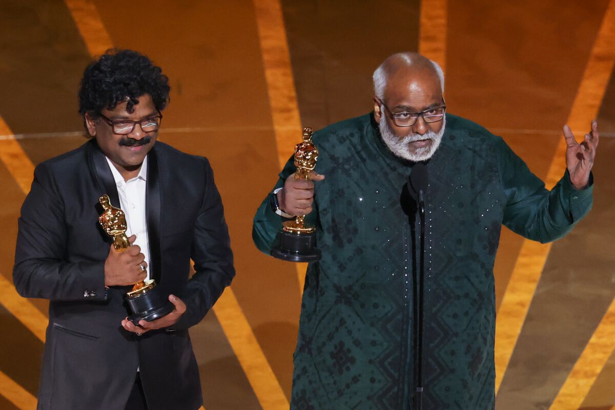 Two men holding Oscars onstage