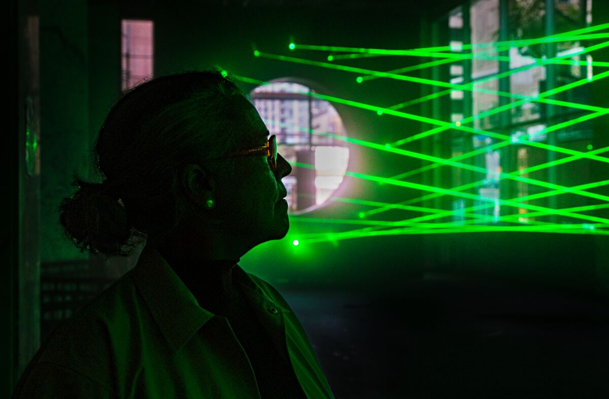 Artist Rita McBride posing with her laser installation at the Hammer Museum. (Ricardo DeAratanha / Los Angeles Times)