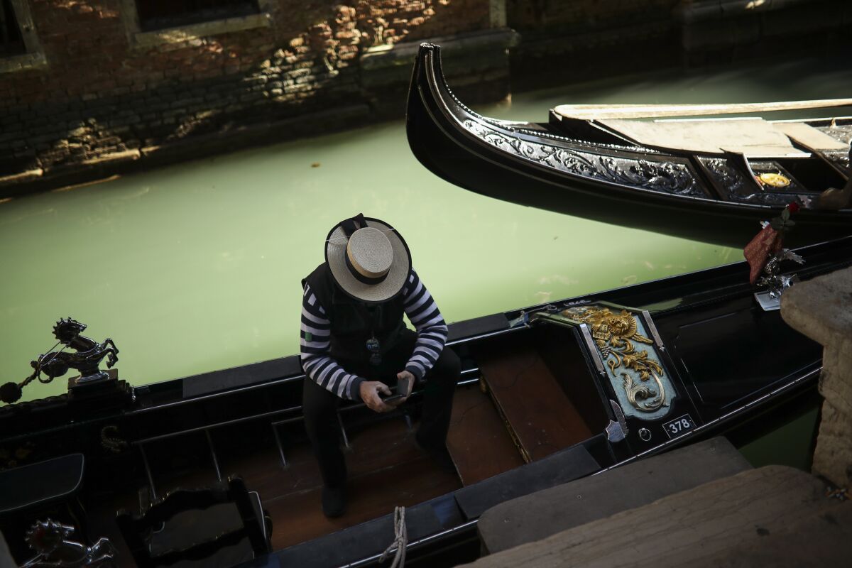 A gondolier looks at his smartphone as he waits for clients in Venice, Italy.