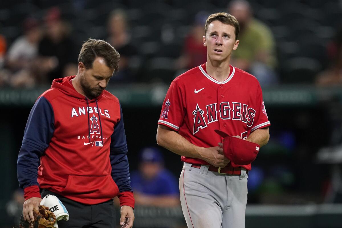 A member of the Angels staff walks off the field with first baseman Matt Duffy.