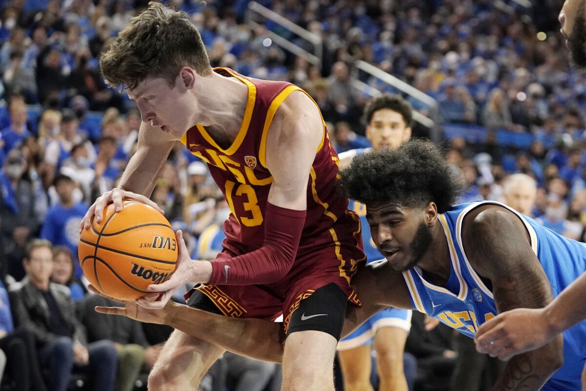 UCLA center Myles Johnson tries to knock the ball from the hands of USC guard Drew Peterson.