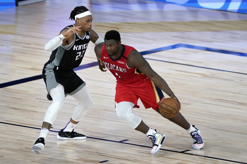 New Orleans Pelicans star Zion Williamson, right, drives to the basket against Sacramento Kings' Richaun Holmes.