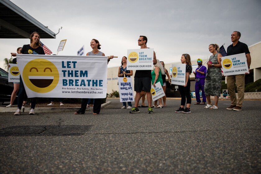 People hold signs protesting face masks requirements in schools