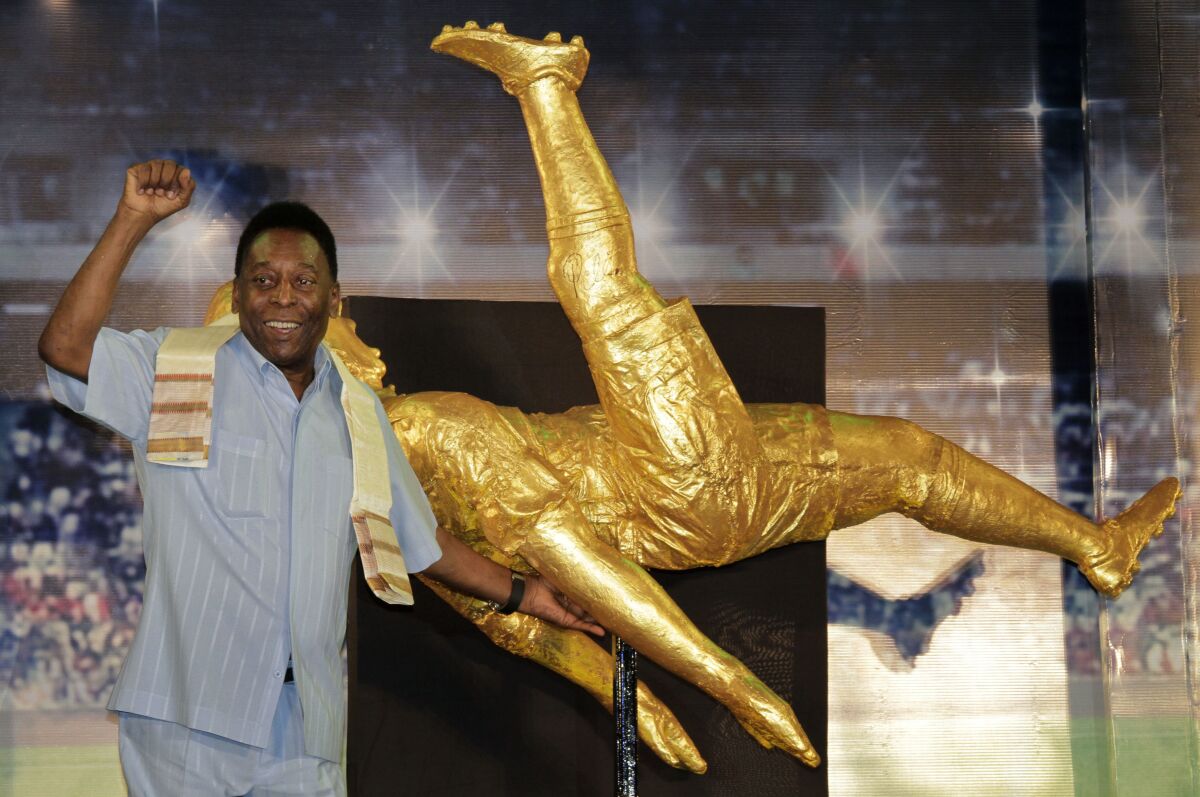Pelé stands near a life-sized statue of him during a visit to India in October 2015.