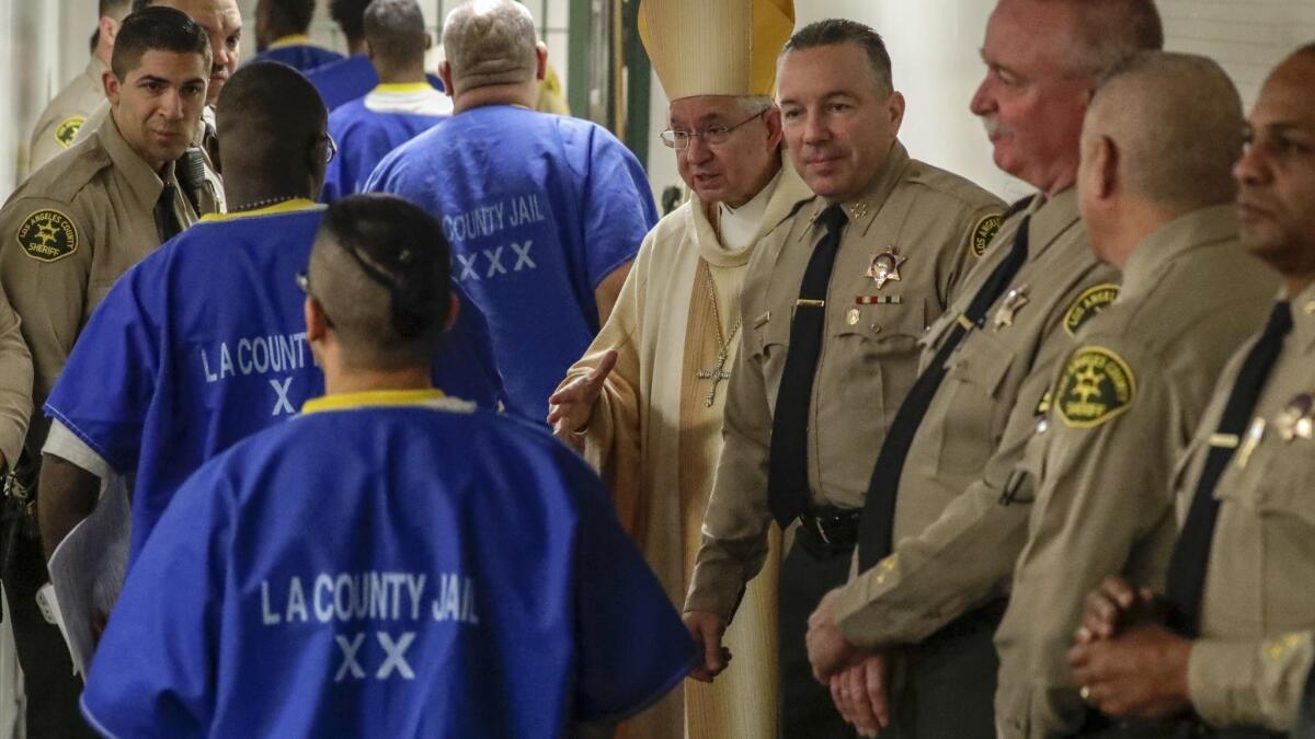 Archbishop Jose H. Gomez, center, and new L.A. County Sheriff Alex Villanueva, fourth from right, greet inmates after a Christmas Mass at Men's Central Jail.