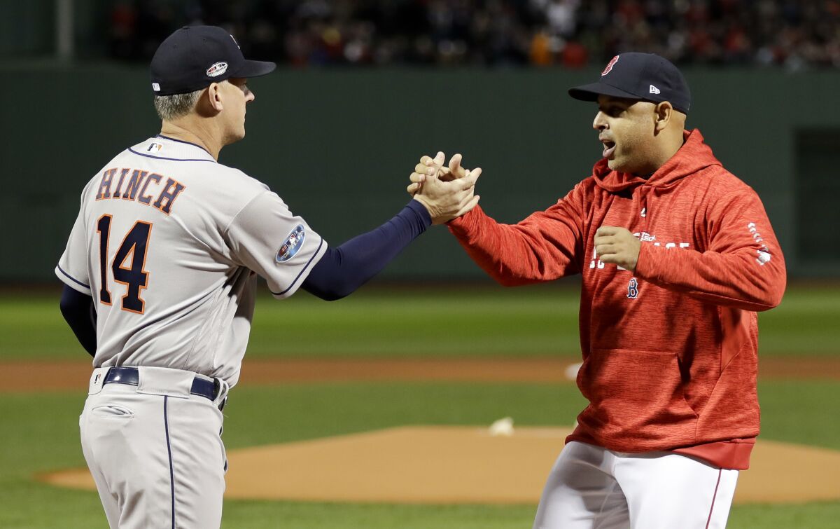 FILE - In this Oct. 13, 2018, file photo, Houston Astros manager AJ Hinch, left, and Boston Red Sox manager Alex Cora shake hands before Game 1 of a baseball American League Championship Series in Boston. Detroit Tigers general manager Al Avila said Friday, Oct. 2, 2020, that Detroit is not ruling out the possibility of hiring A.J. Hinch or Alex Cora for its managerial vacancy. Hinch and Cora were suspended this season for their roles in the Houston Astros' sign-stealing scandal. (AP Photo/David J. Phillip, File)