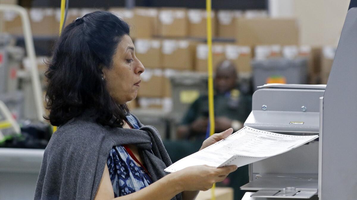 An election worker feeds ballots into a tabulation machine at the Broward County Supervisor of Elections office on Saturday.