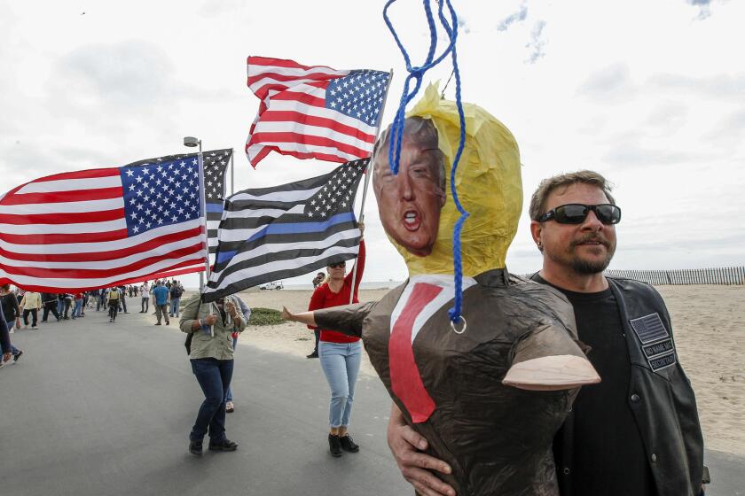Mick White rescues a President Trump prop created by anti-Trump protesters during the Make America Great Again rally in Huntington Beach.