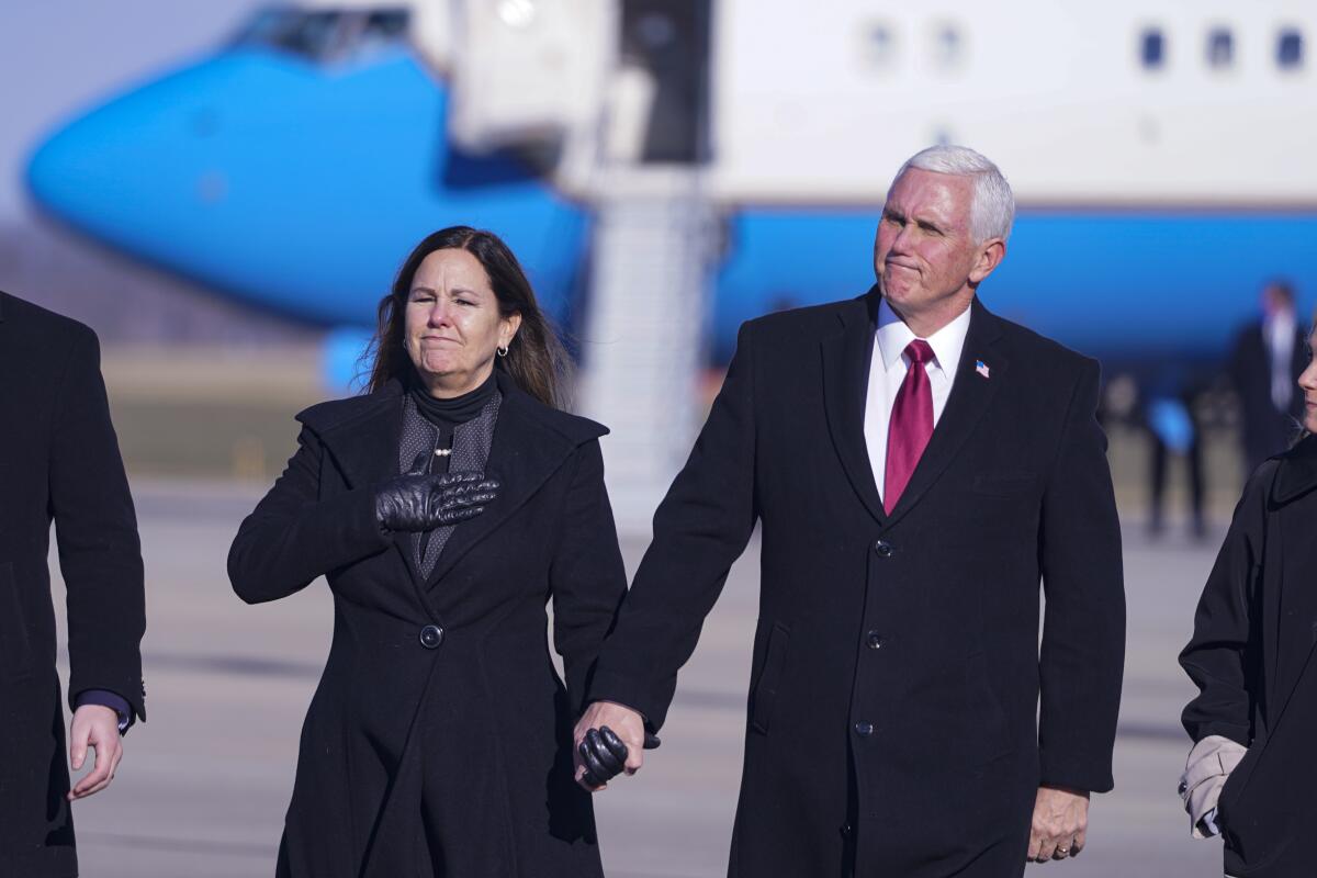 Mike Pence and Karen Pence hold hands as they walk on an airport tarmac.