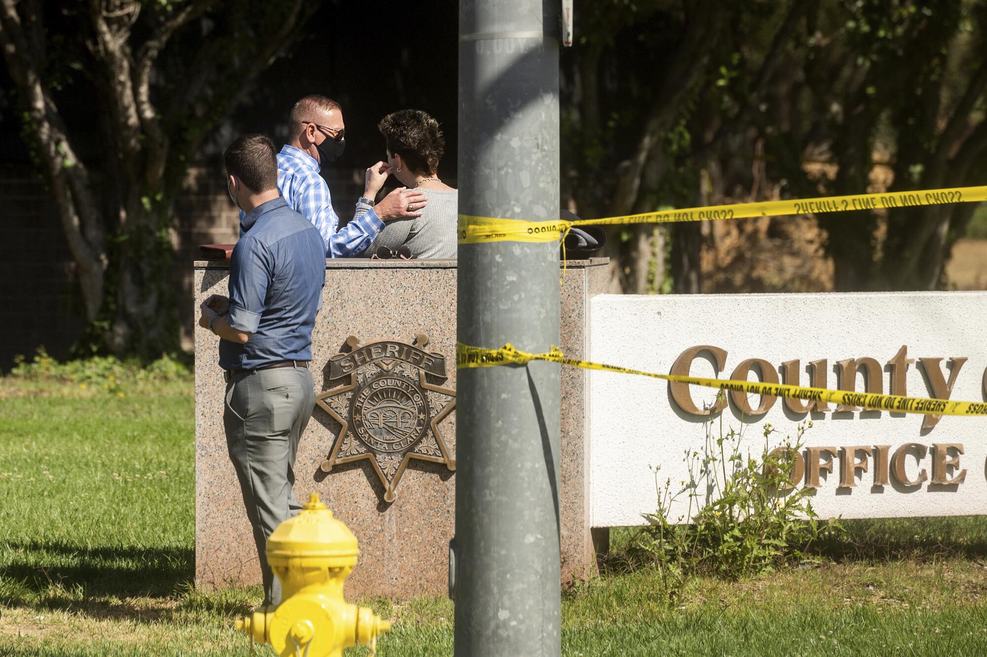 Three people stand near a low structure with the words "County Office."