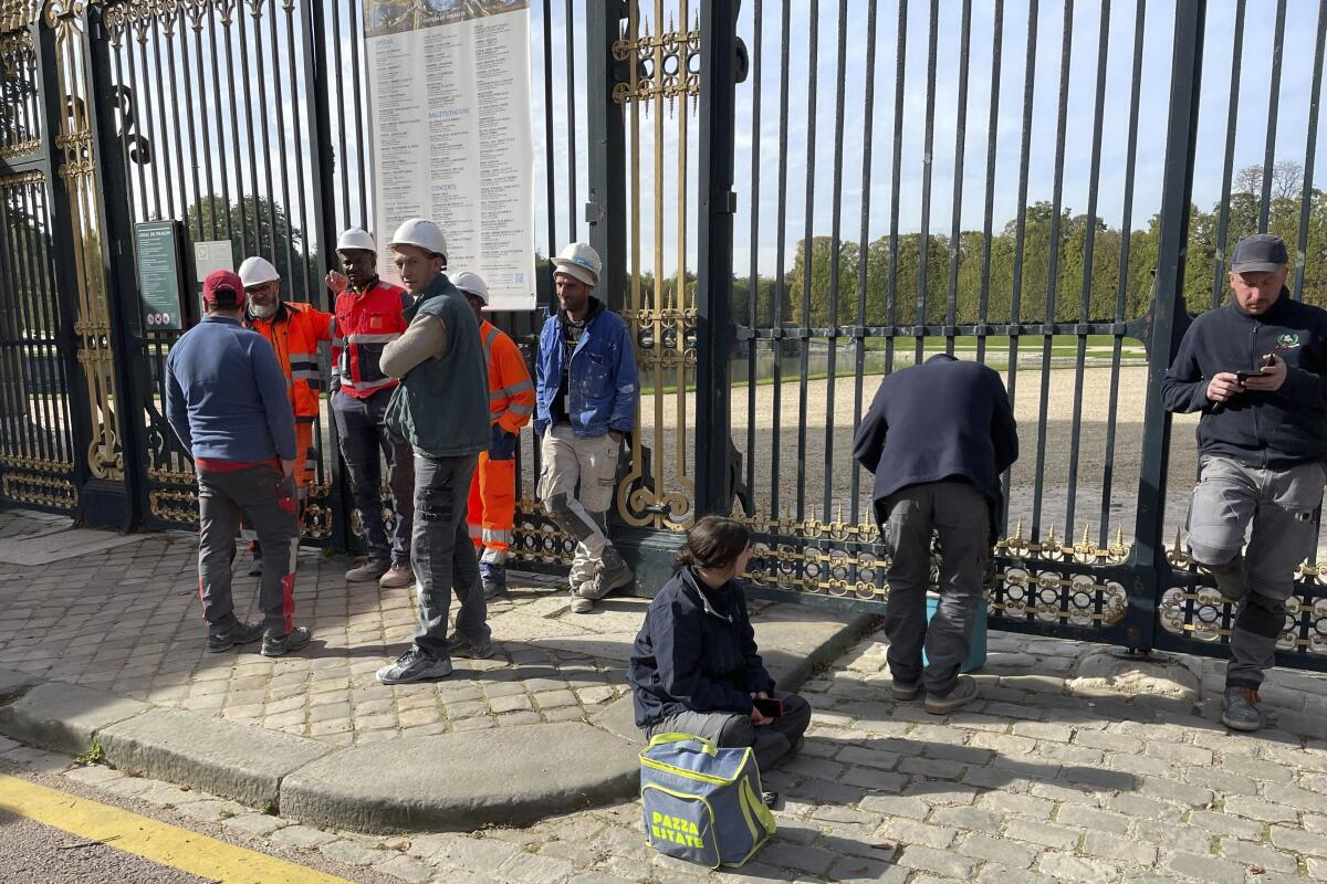 Workers wait outside the gate at the Palace of Versailles during evacuation