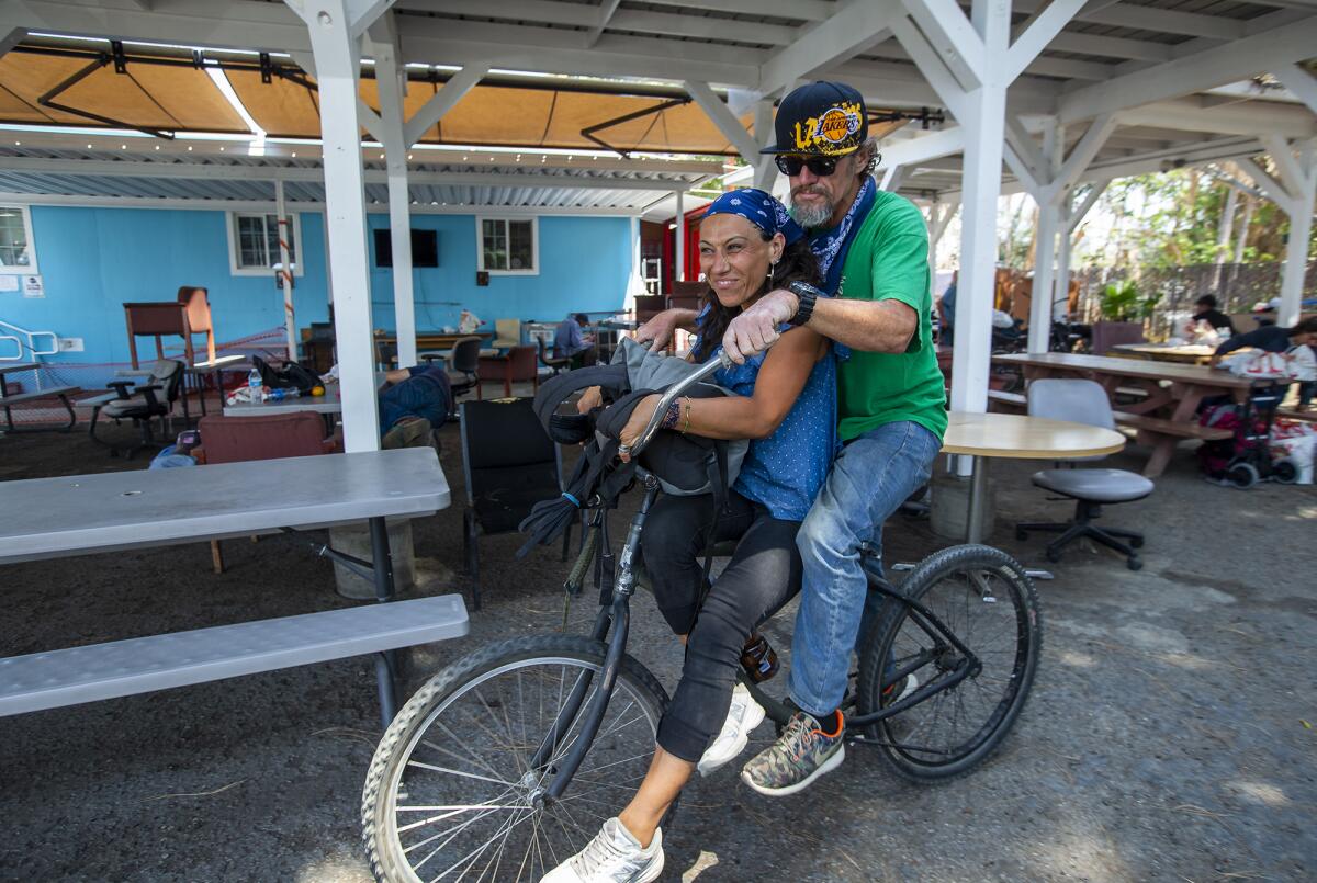 Craig Lasky and America Sanchez ride a bike at Mary's Kitchen in Orange.