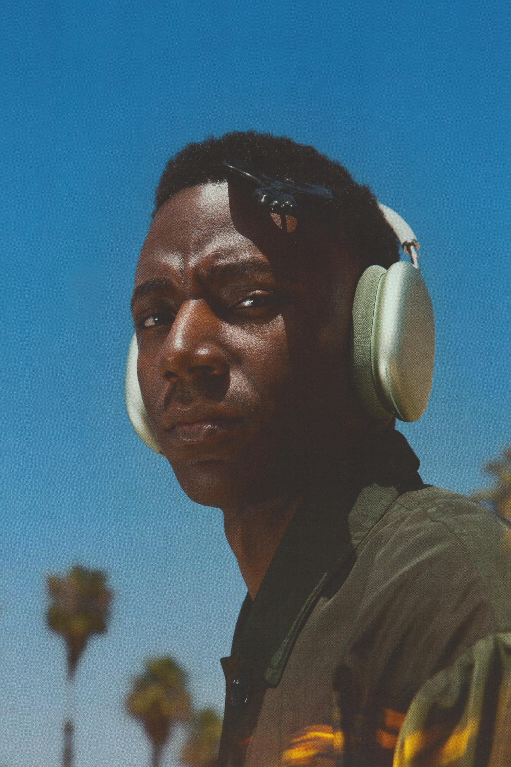 A man is seen against the blue sky wearing headphones 