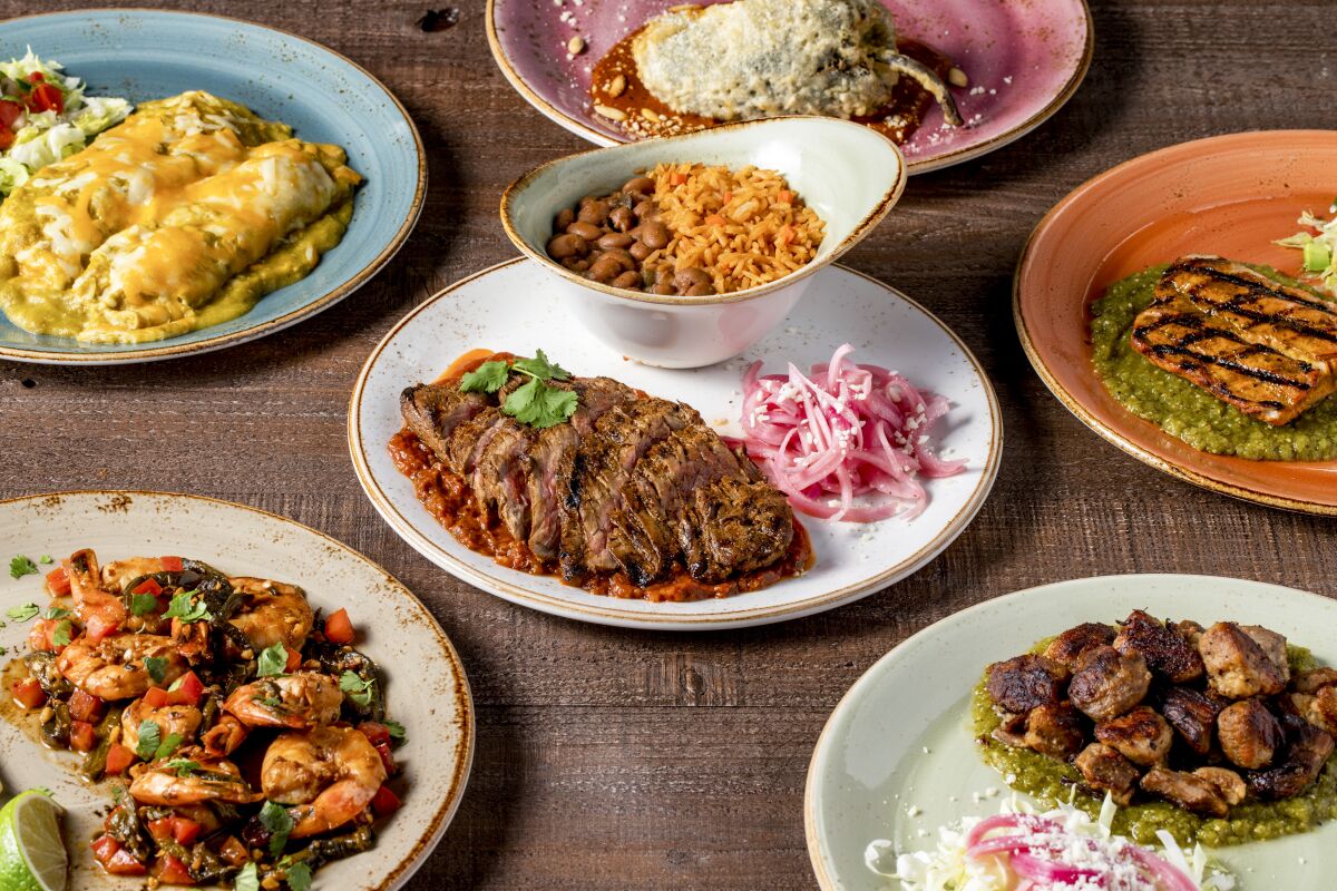 A photo of a spread of Mexican dishes on a tabletop: chile relleno, enchiladas, carne asada and more.