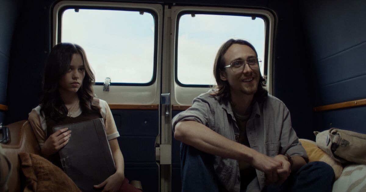 A young woman and man sit in the back of a van.
