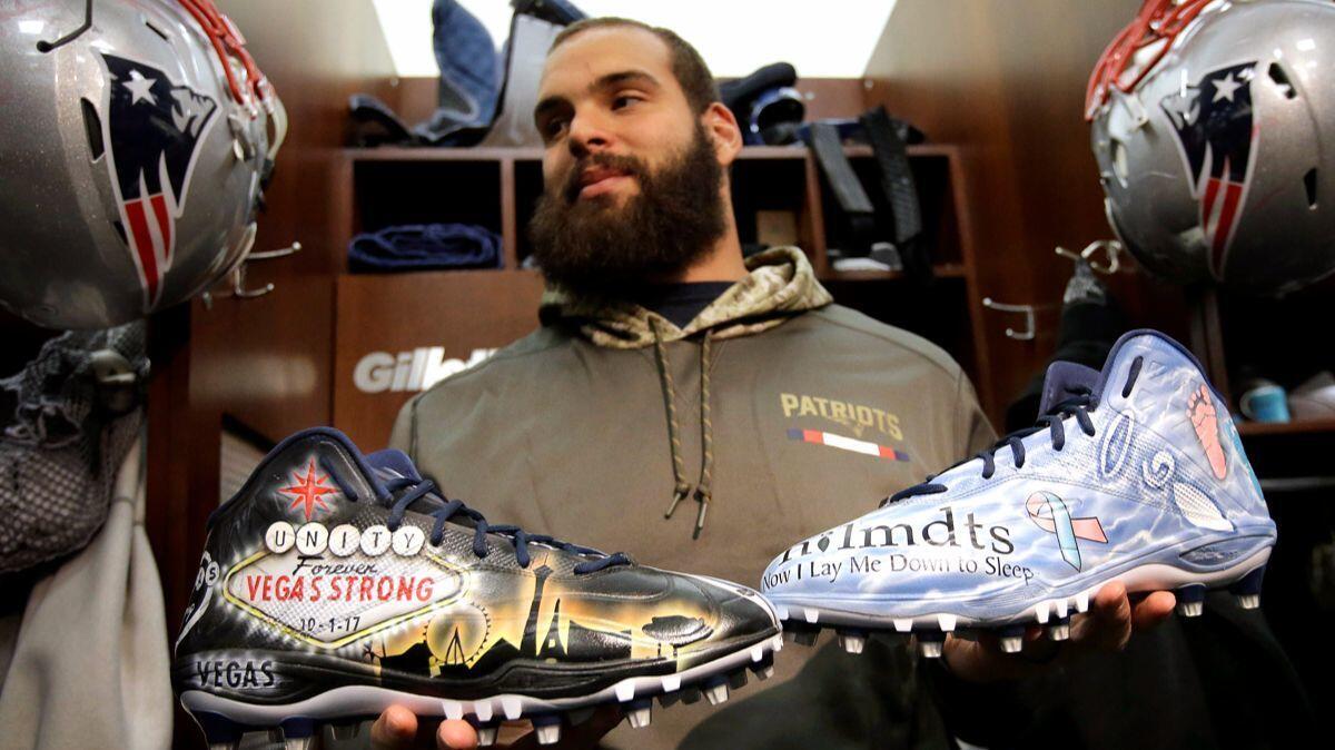 New England Patriots defensive end Lawrence Guy displays cleats that honor victims of the October Las Vegas shooting, left, and families who have lost an infant, right, in the team's locker room following an NFL football practice.