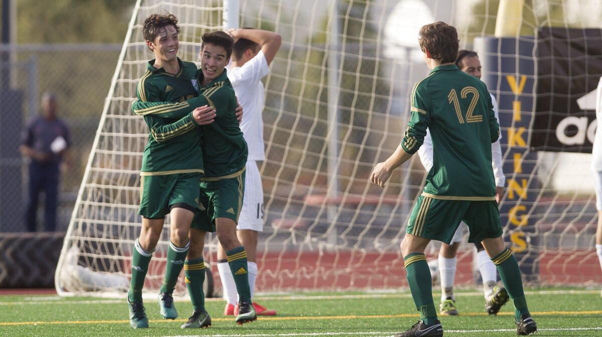 Edison High’s Chase Bullock, left, is embraced by teammate Zac Ingalls after he increased the Chargers’ lead, 2-0, during the first half against Marina in a Sunset League game in Huntington Beach. Ingalls scored the first goal for Edison.