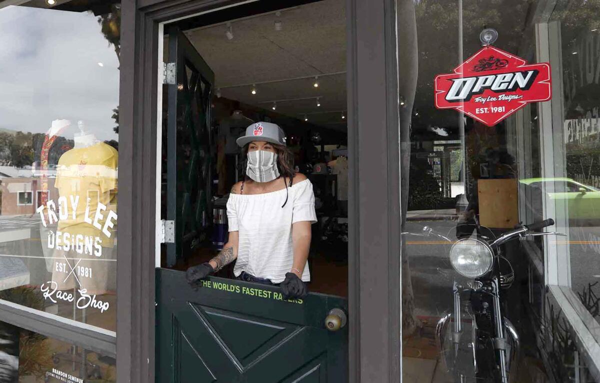 Manager Carmalit Green looks out the door of Troy Lee Designs and Race Shop store in downtown Laguna Beach, as California entered Stage 2 of reopening Friday with the permission of Gov. Gavin Newsom.