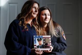 Pamela Yarosz and her daughter Capri are shown with a photo of New York firefighter Christopher Michael Mozzillo Saturday, Sept. 7, 2024, in Freehold, N.J.. Mozzillo, who died in the 9/11 attacks, was Pamela's brother. (AP Photo/Noah K. Murray)