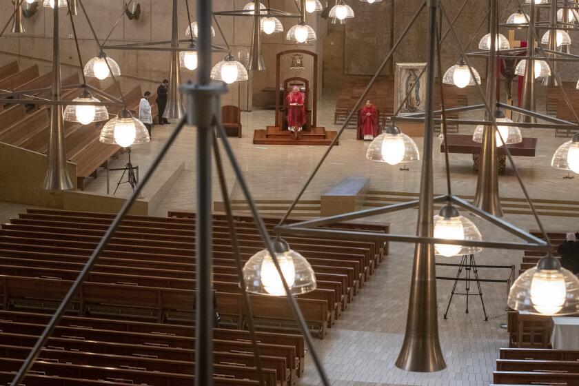 LOS ANGELES, CA - APRIL 10: Archbishop Jose Gomez, Father Brian Nunez and Father Raymont Medina celebrate Good Friday liturgy in a nearly empty Cathedral of Our Lady of the Angels to guard against the coronavirus on Friday, April 10, 2020 in Los Angeles, CA. (Brian van der Brug / Los Angeles Times)