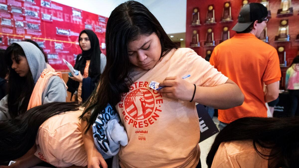 Kate Cruz, 16, a high school student at the Miguel Contreras Learning Complex, puts on a sticker after preregistering to vote during the Girls Build summit at USC.
