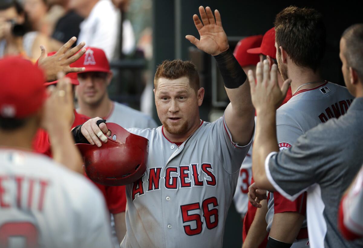 Angels' Kole Calhoun high-fives teammates in the dugout after scoring against Baltimore on July 8.