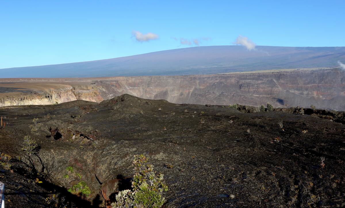ARCHIVO - El volcán Mauna Loa, al fondo, se alza por encima del cráter del volcán Kilauea,