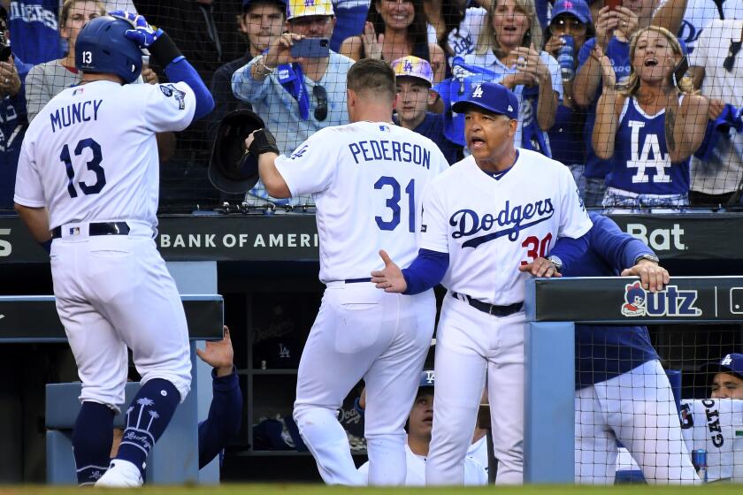Wally Skalij??Los Angeles Times MANAGER Dave Roberts congratulates Max Muncy after the player’s two-run home run in Game 5 against Washington. The Dodgers have won NL West championships in each of Roberts’ four seasons at the helm.