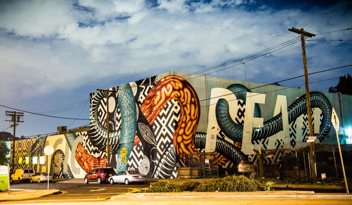 An exterior photograph of a building covered with a colorful mural of a serpent.