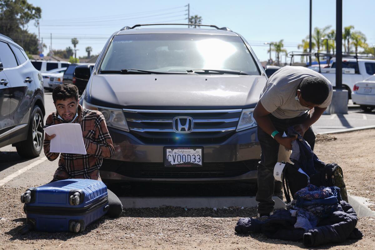 Dos inmigrantes revisan su equipaje en un estacionamiento tras ser detenidos 