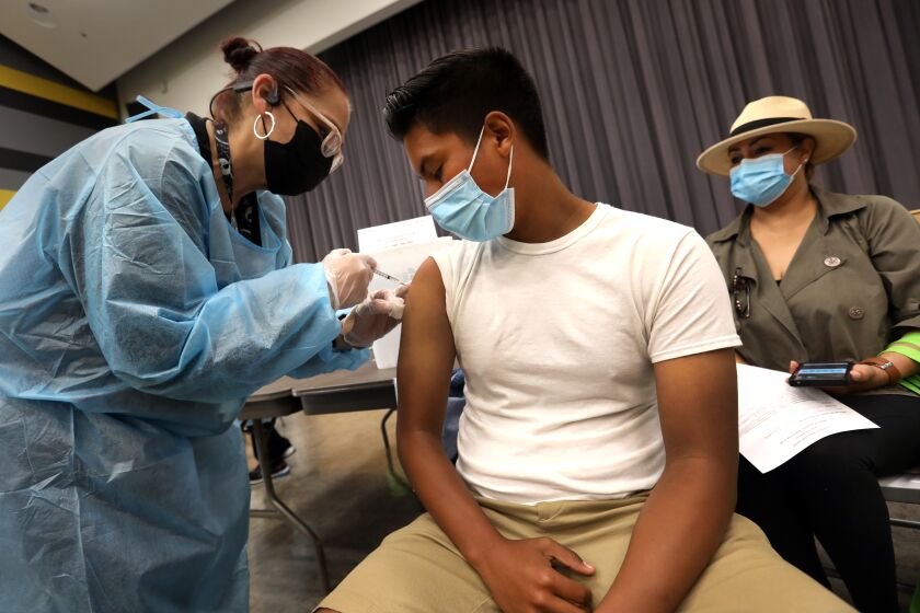 San Pedro—May 24, 2021—D’Marco Ahumada, age 16, gets his first vaccine at San Pedro High School on May 24, 2021. San Pedro Senior High school is one of the Los Angeles County Unified schools providing coronavirus vaccines for children 12 and up. (Carolyn Cole / Los Angeles Times)