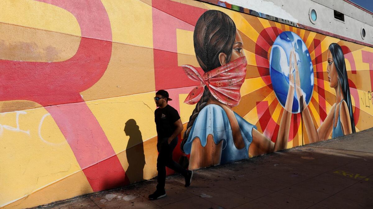 A man walks past a mural painted on the wall of Self Help Graphics & Art in Boyle Heights.