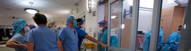 Nurses stand to assist doctors and nurses inside the negative pressure room.
