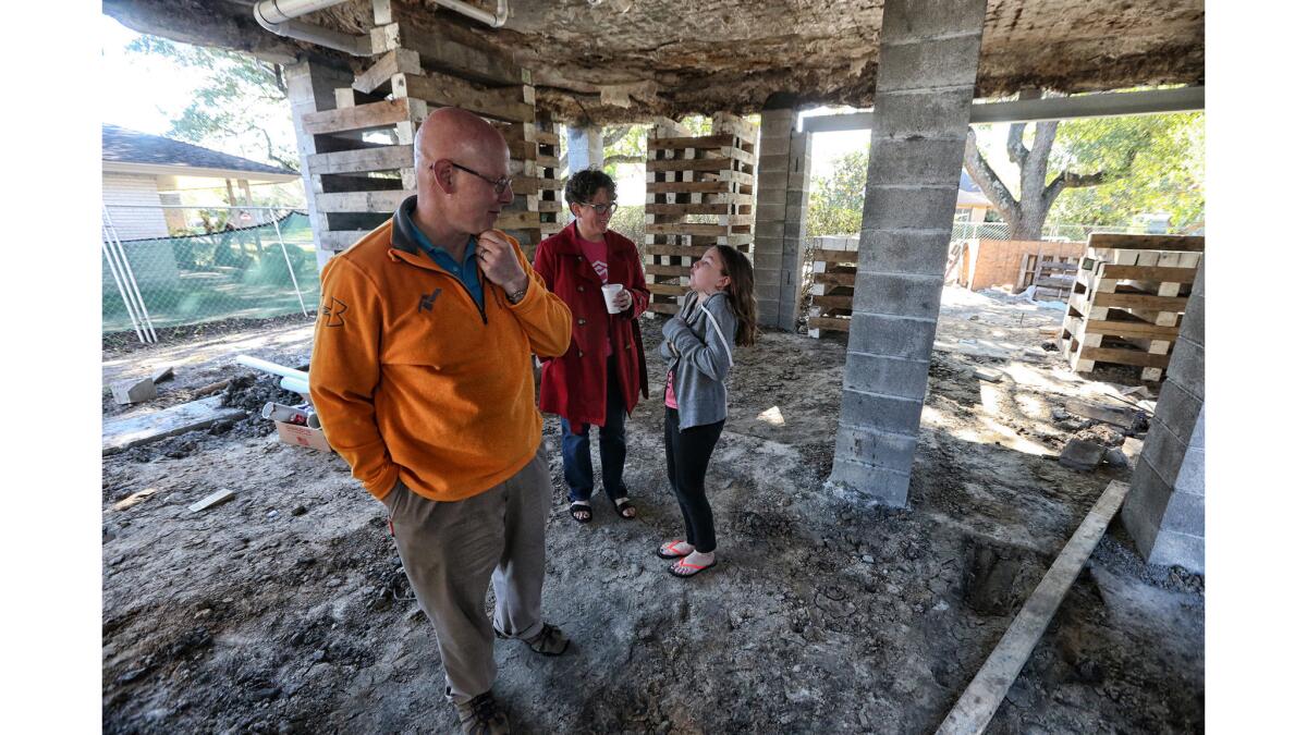 Drew Shefman, his wife, Pam, and daughter Quinn underneath their home. Shefman elevated his entire house on jacks just before Hurricane Harvey arrived. His home suffered no damage.