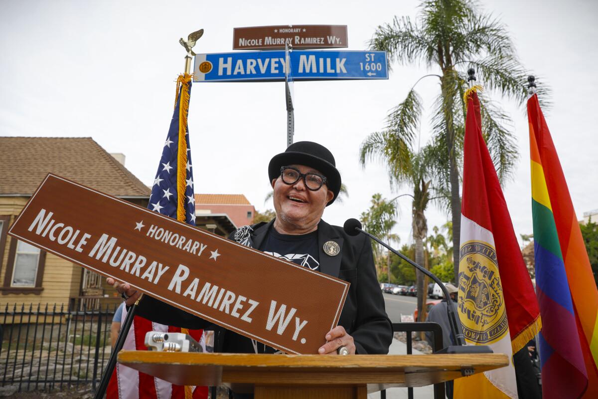Longtime LGBTQ and civil rights activist Nicole Murray Ramirez holds a street sign.