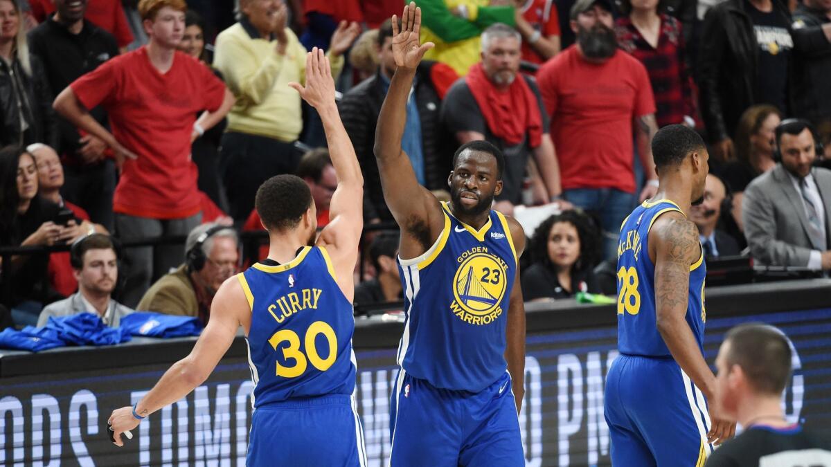 Golden State Warriors' Stephen Curry (30) high fives Draymond Green (23) during the second half against the Portland Trail Blazers in Game 4 of the NBA Western Conference Finals on May 20 in Portland, Ore.