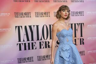Taylor Swift poses in a light blue dress against a pink backdrop.