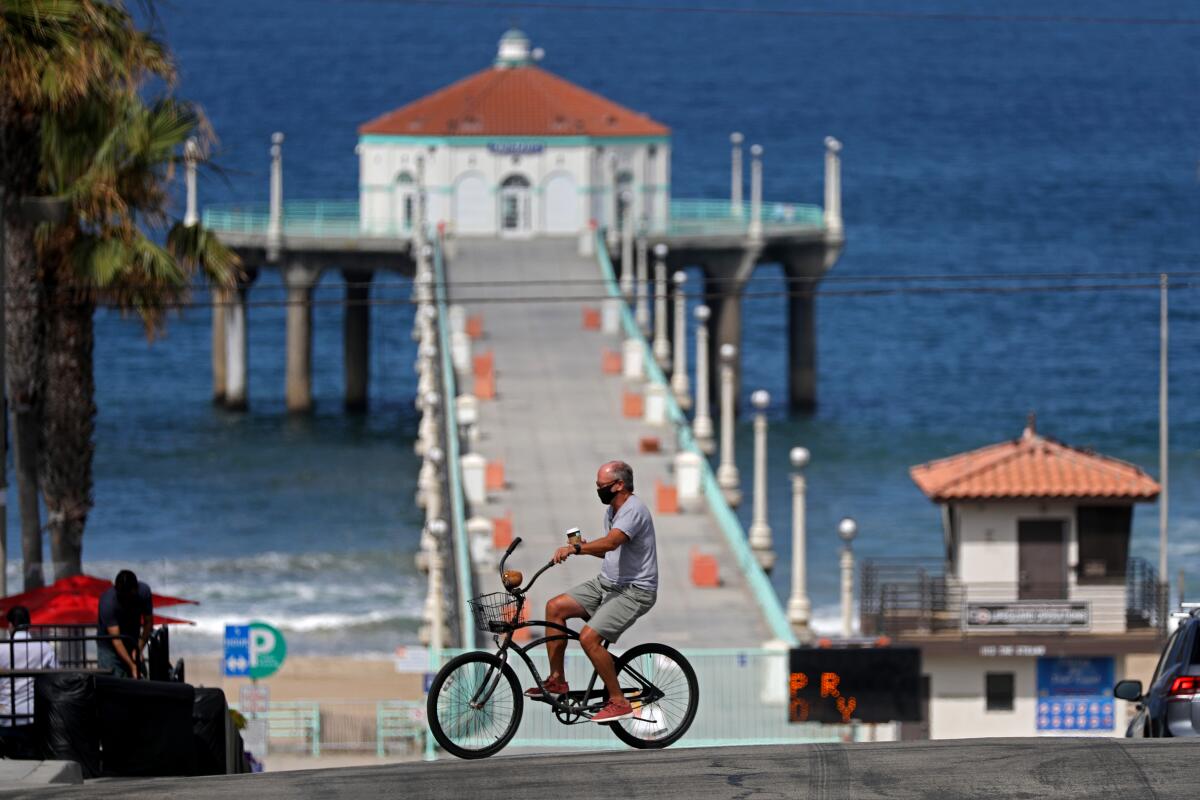 A bicyclist rides near the closed pier in Manhattan Beach on Friday, July 3, 2020.