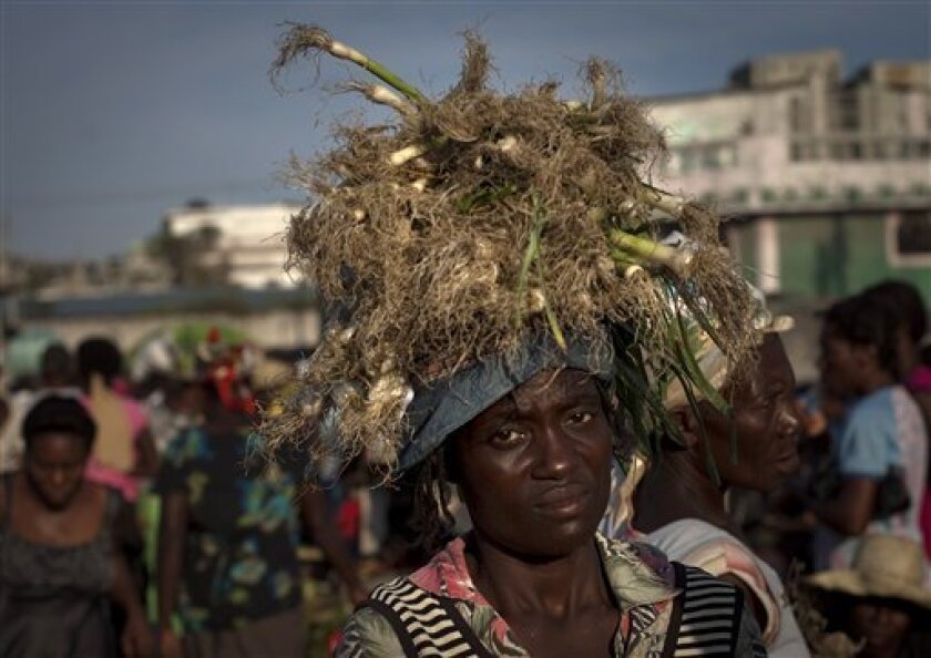 In this April 21, 2011 photo, a garlic vendor balances produce on her head as she walks through La Saline Market in Port-au-Prince, Haiti. Soaring food prices aren't new in Haiti, the poorest country in the Western Hemisphere and heavily dependent on imports. In 2011, prices are on the rise again, mirroring global trends, and the cost of gasoline has doubled to $5 a gallon. Haitians are paying more for basic staples than much of Latin America and the Caribbean, an Associated Press survey finds. (AP Photo/Ramon Espinosa)