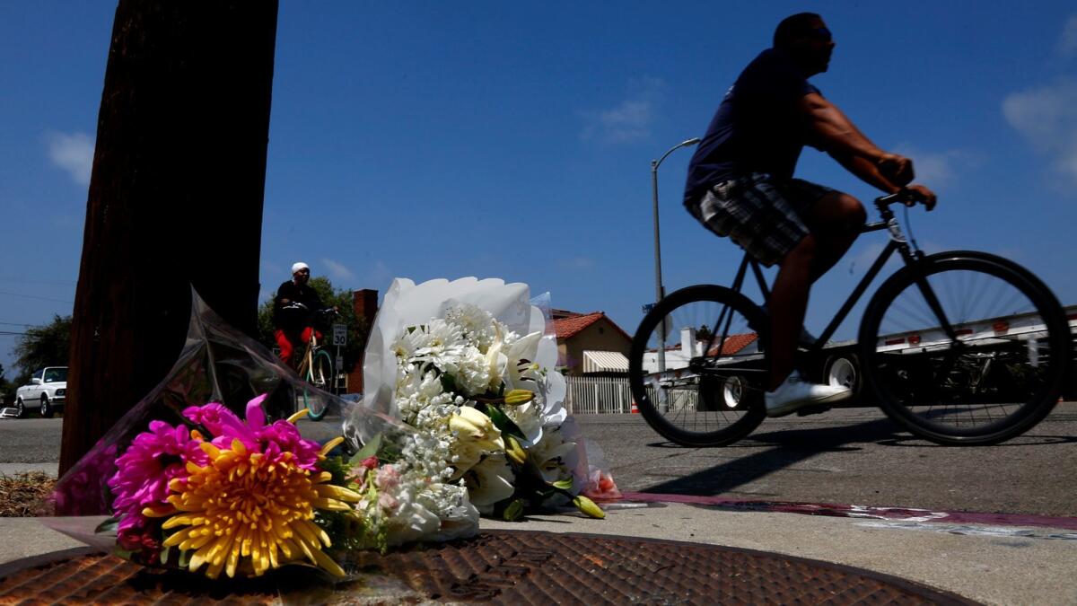 Bikers ride past a memorial left Aug. 5 for Marvin Ponce, who was shot to death at the corner of 7th and Brooks avenues.
