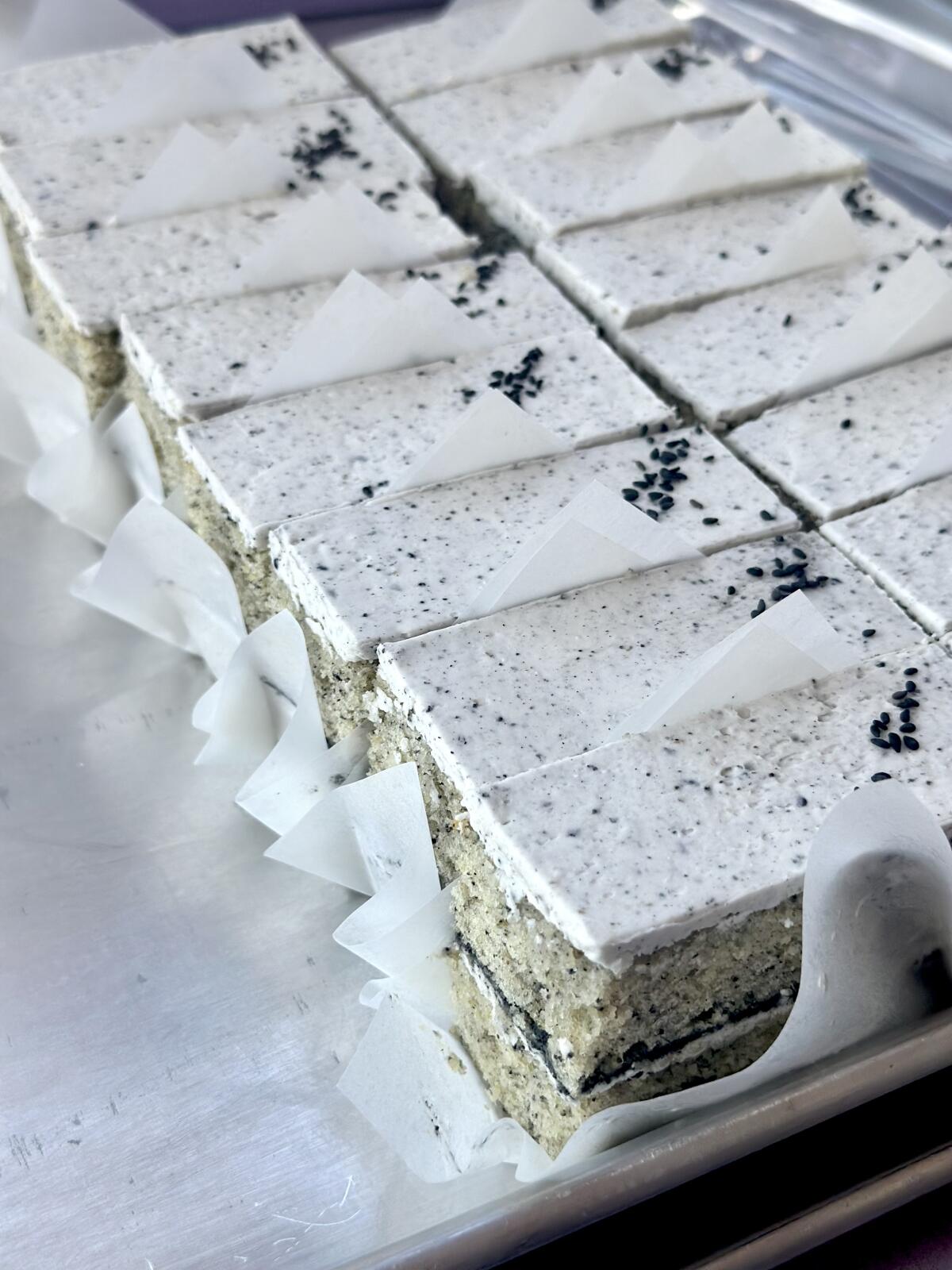 Black sesame cake with white frosting sliced into rectangular bars