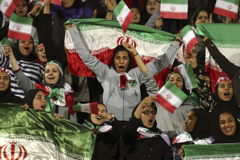 FILE - In this Oct. 16, 2018 file photo, Iranian women cheer as they wave their country's flag after authorities in a rare move allowed a select group of women into Azadi stadium to watch a friendly soccer match between Iran and Bolivia, in Tehran, Iran. Sahar Khodayari, an Iranian female soccer fan died after setting herself on fire outside a court after learning she may have to serve a six-month sentence for trying to enter a soccer stadium where women are banned, a semi-official news agency reported Tuesday, Sept. 10, 2019. The 30-year-old was known as the "Blue Girl" on social media for the colors of her favorite Iranian soccer team, Esteghlal. (AP Photo/Vahid Salemi, File)