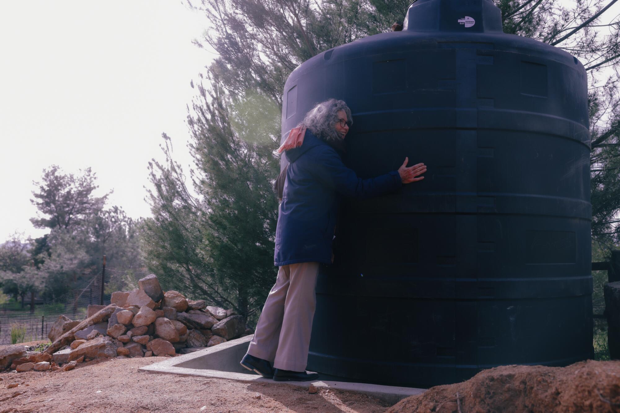 Winemaker Ivette Vaillard hugs a water storage tank 