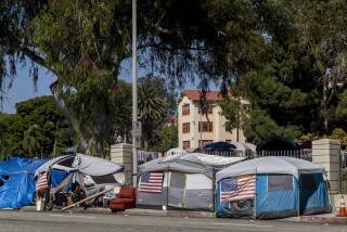 WEST LOS ANGELES, CA - AUGUST 30: A homeless encampment outside the West L.A. Veterans Affairs facilities on Monday, Aug. 30, 2021. The encampment is on San Vicente Boulevard in an unincorporated area near Brentwood in West Los Angeles, CA. Dozens of veterans live at the encampment, sometimes called Veterans Row, where some tents are decorated with U.S. flags. Recently a homeless veteran had been stapped to death near by. (Francine Orr / Los Angeles Times)