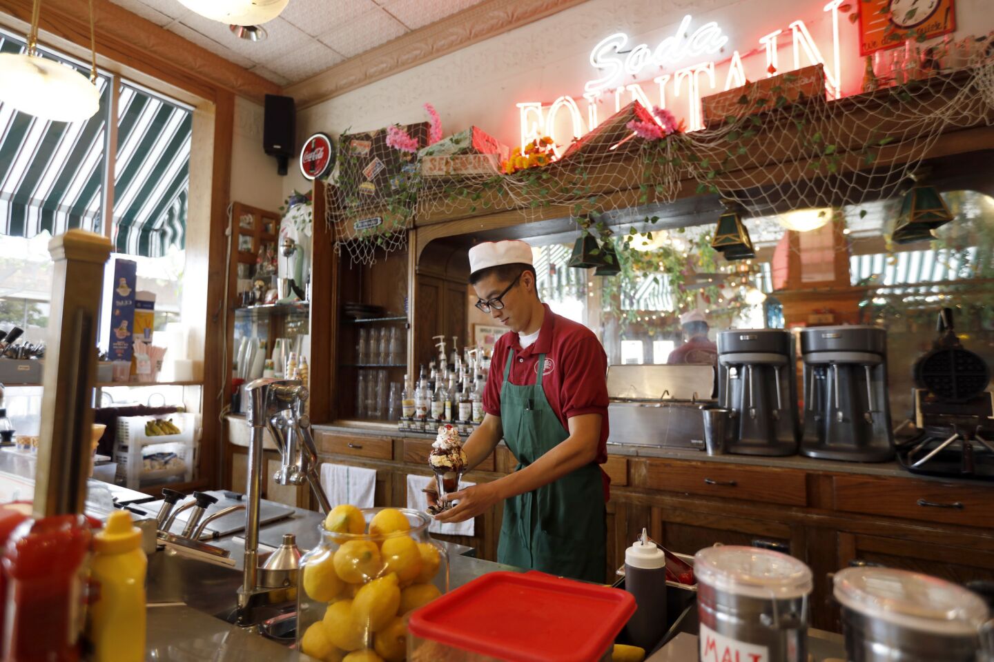 SOUTH PASADENA, CA APRIL 11, 2019: Tristan Yi, 24, is making a hot fudge Sunday at the old fashioned soda fountain inside the Fair Oaks Pharmacy in South Pasadena CA April 11, 2019. (Francine Orr/ Los Angeles Times)