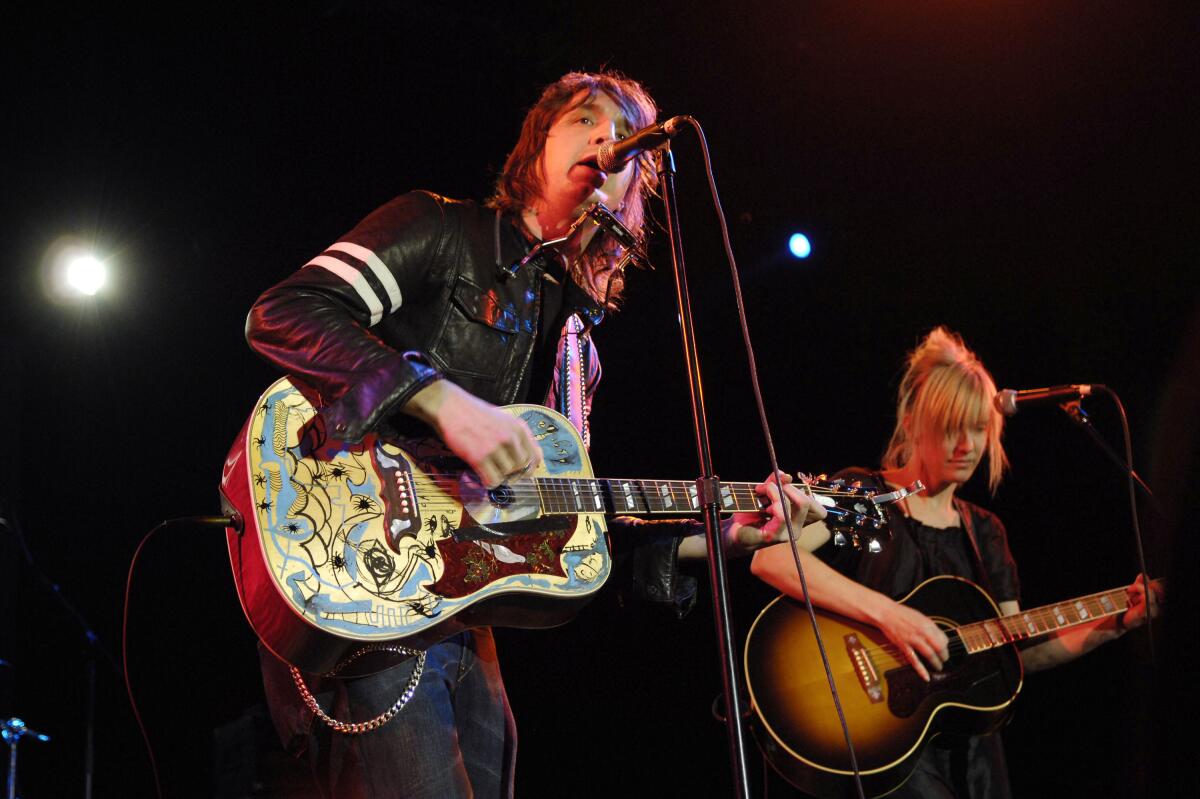 A man and a woman playing guitars onstage.