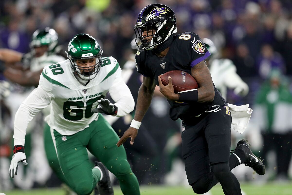 Baltimore Ravens' quarterback Lamar Jackson (8) carries the ball against New York Jets defensive end Jordan Willis (60) during the game on Thursday in Baltimore.