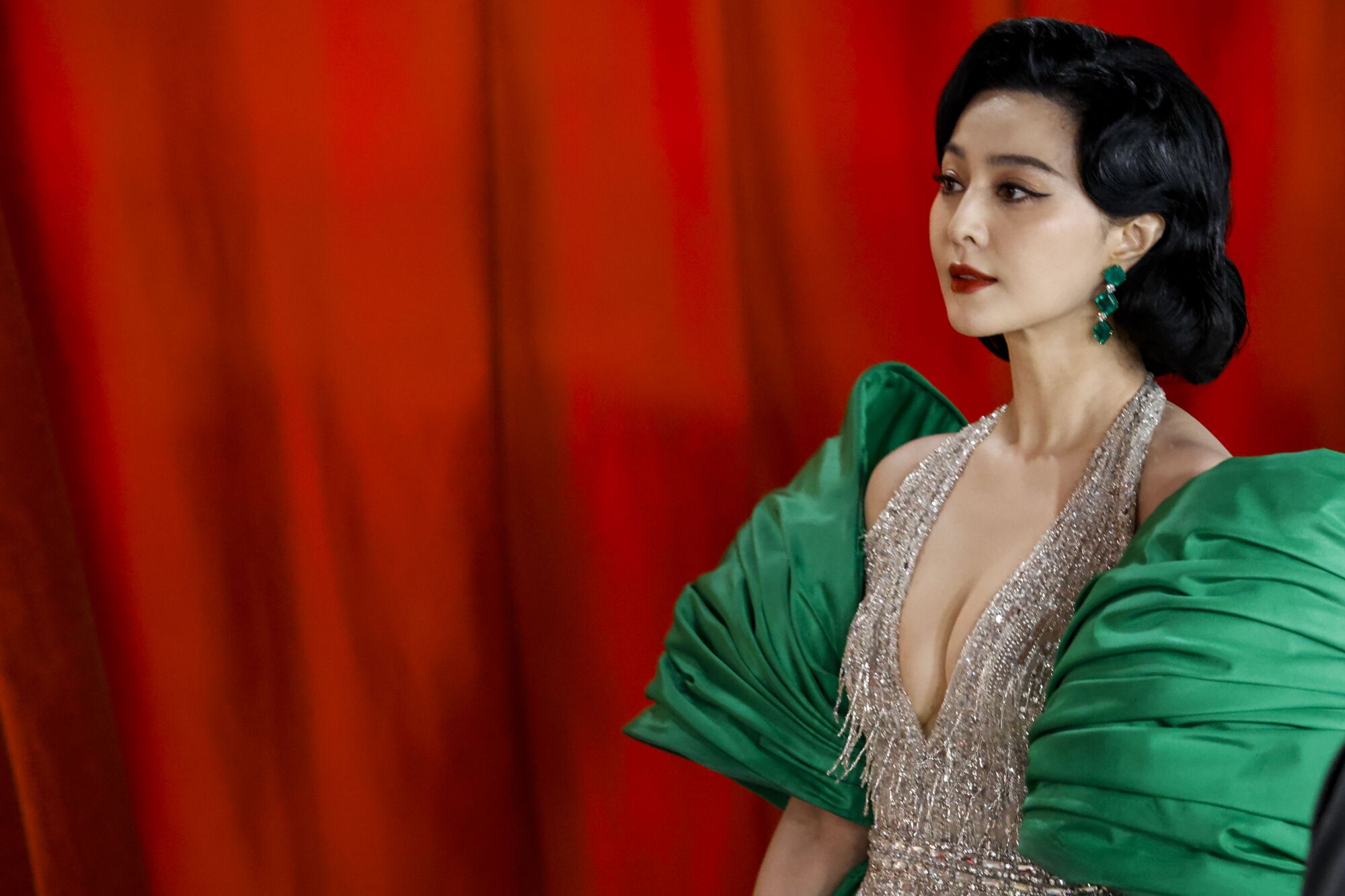 Fan Bingbing wears a shimmering silver dress with emerald green satin and cape-like puffs on her shoulders. 